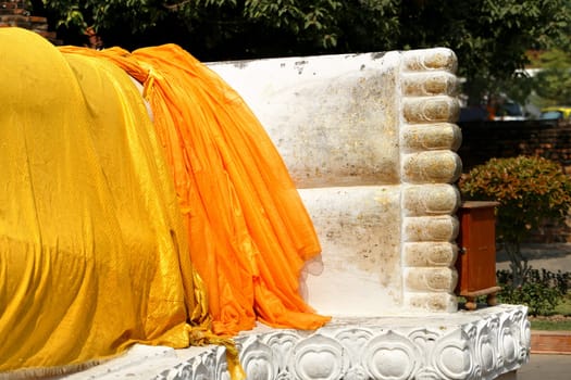 Feet statue of Buddha looks out from under a yellow cloth