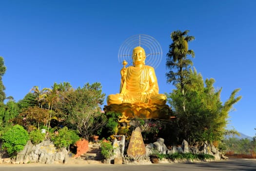 Giant sitting golden Buddha holding golden lotus at a Mahayana Buddhist temple in Dalat, Vietnam