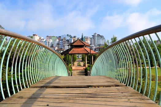 Bridge leading to a pavillon in flower park with Central Dalat in the background, Dalat, Vietnam