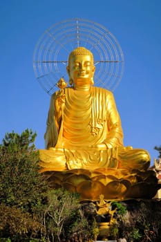 Giant sitting golden Buddha holding golden lotus at a Mahayana Buddhist temple in Dalat, Vietnam
