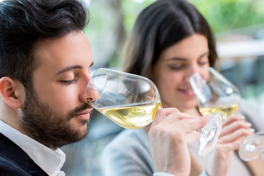 Close up portrait of young couple tasting white wine tasting.