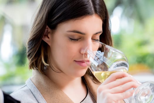 Close up portrait of attractive young woman searching for aroma in white wine at tasting.