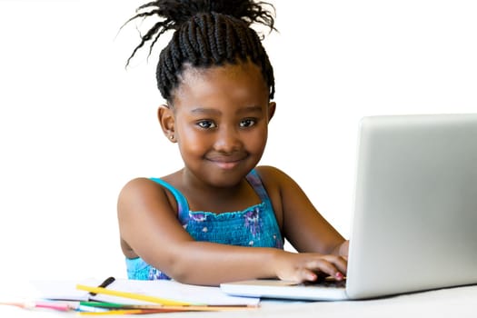 Close up portrait of little african girl sitting at desk with hands on keyboard.Isolated on white background.