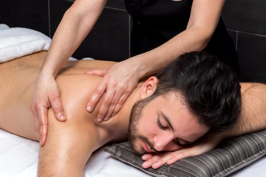 Close up of osteopath massaging young man’s back.