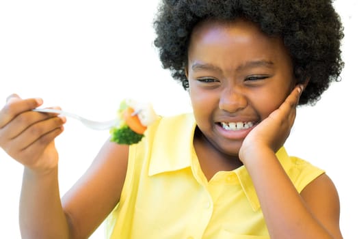 Close up portrait of little african girl refusing to eat fork with vegetables.Child pulling up nose Isolated on white background.
