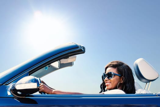 Close up portrait of young african girl taking blue convertible for a test drive.