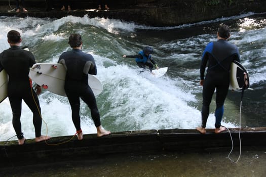 In the English Garden in Munich,many surfers surf on the surfboard in the Eisbach on the Eisbach wave. Surfing on the surfboards is fun. Leisure Sports River Surfing Keep Surfing Eisbach Bridge Bus Stop National Museum Haus der Kunst