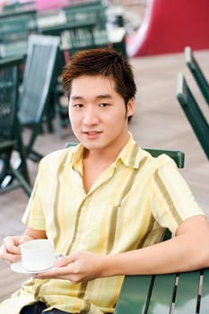 Portrait of a young man holding a coffee cup and a saucer