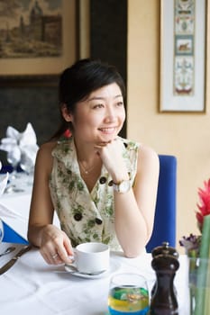 Young woman sitting in a restaurant with her hand on her chin