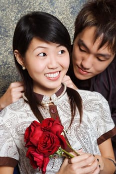 Close-up of a young man tying a necklace around a young womanŽs neck