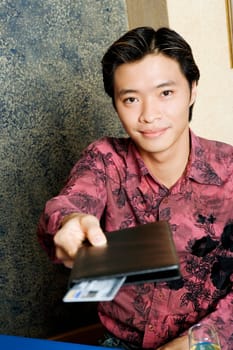 Portrait of a young man paying with a credit card in a restaurant