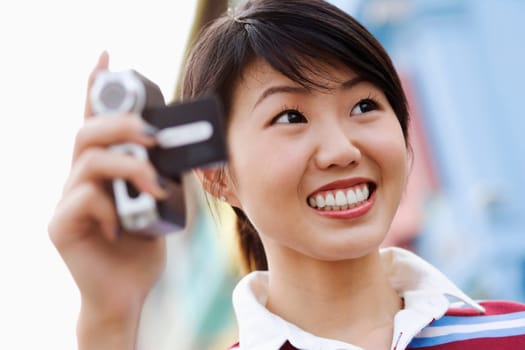 Close-up of a young woman holding a digital camera