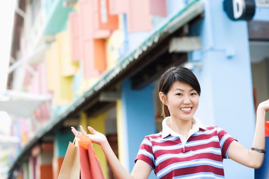 Close-up of a young woman holding shopping bags and smiling