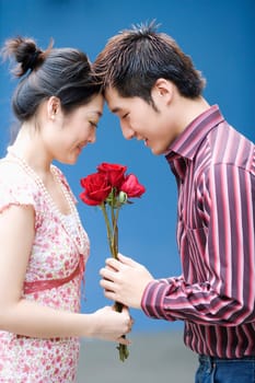 Side profile of a young man giving roses to a young woman