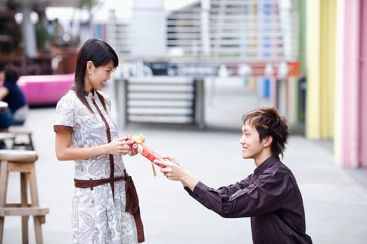 Side profile of a young man giving a gift to a young woman