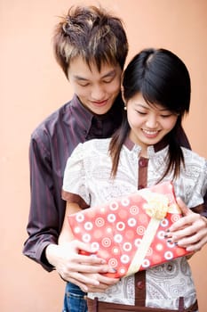 Close-up of a young couple holding a gift and smiling