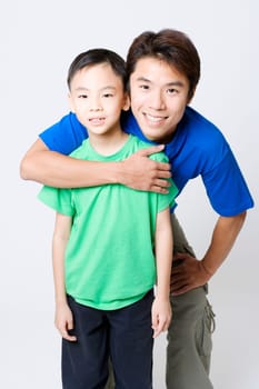 Portrait of a mid adult man hugging his son from behind