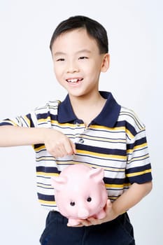 Close-up of a boy putting a coin into a piggy bank