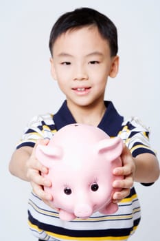 Portrait of a boy holding a piggy bank