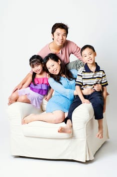Portrait of a mid adult man and a young woman sitting in an armchair with their son and daughter