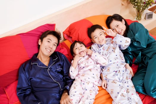Portrait of two parents lying on the bed with their two children