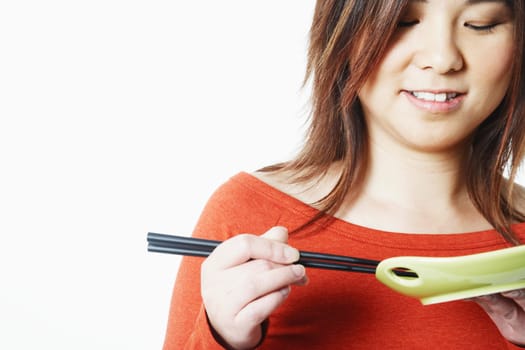 Close-up of a mid adult woman holding chopsticks and a plate