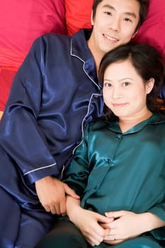 Portrait of a mid adult man lying on the bed with a young woman