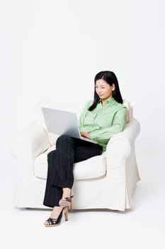 Businesswoman sitting in an armchair and using a laptop