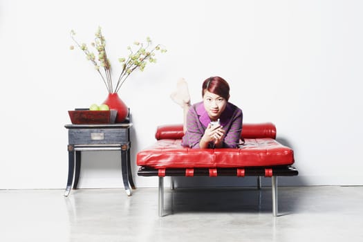 Portrait of a young woman lying on the bed holding a mobile phone