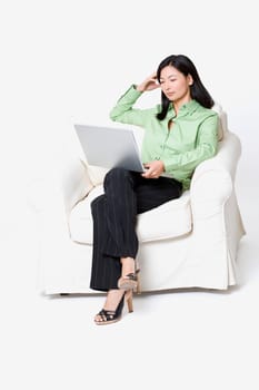 Businesswoman sitting in an armchair and using a laptop