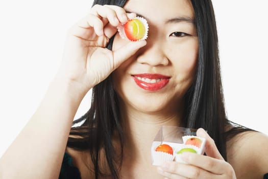 Portrait of a young woman holding candy in front of her eye
