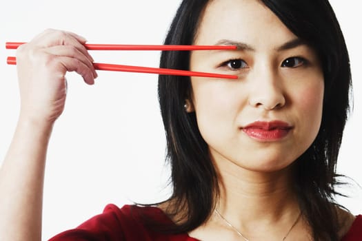 Portrait of a young woman looking through chopsticks