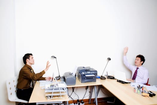 Two businessmen sitting face to face with their hands raised