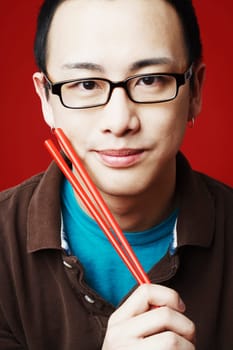 Portrait of a young man holding chopsticks