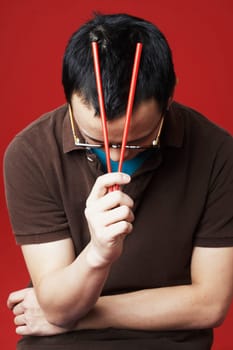 Close-up of a young man holding chopsticks on his head