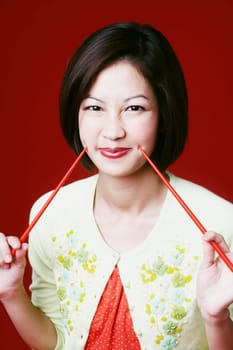 Portrait of a young woman holding chopsticks