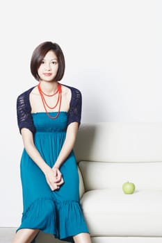 Portrait of a young woman sitting on the arm of an arm chair