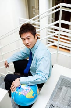 Portrait of a businessman sitting on steps with a globe