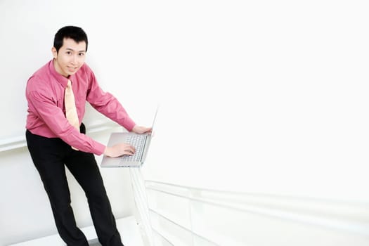 Portrait of a businessman using a laptop on a railing