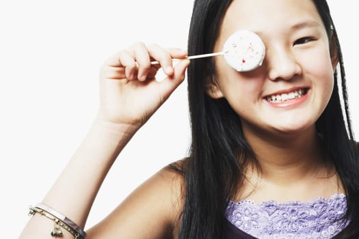 Portrait of a teenage girl covering her eye with a lollipop