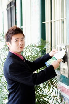 Portrait of a businessman dropping mails into a mailbox