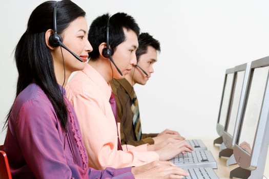 Three customer service representatives working on computers