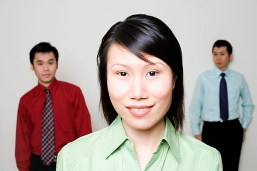 Portrait of a businesswoman smiling with two businessmen standing behind her
