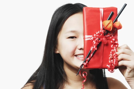 Portrait of a teenage girl holding a gift in front of her face