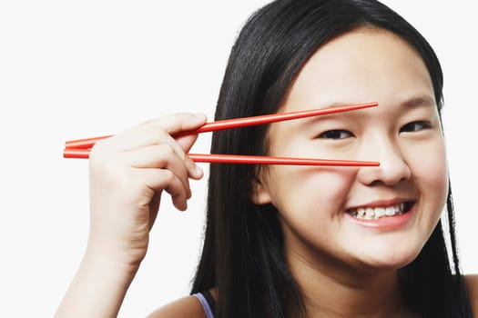 Portrait of a teenage girl looking through chopsticks