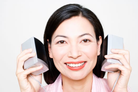 Portrait of a mid adult woman listening to music and holding speakers