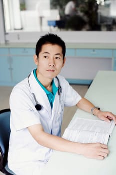 Side profile of a male doctor sitting at the table and holding a book