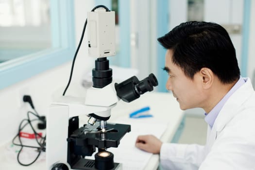 Side profile of a male doctor looking into a microscope