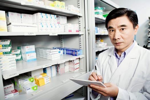 Portrait of a male pharmacist writing in a store room