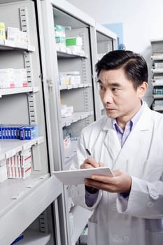 Male pharmacist writing in a store room